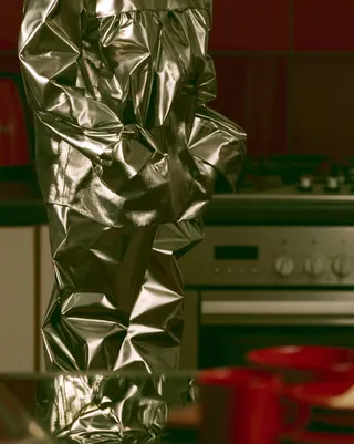 a fashion editorial featuring hand-knitted metallic outerwear in a quiet suburban kitchen preview
