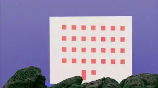 a brutalist seaside hotel perched above black volcanic rocks at blue hour, tiny amber windows preview